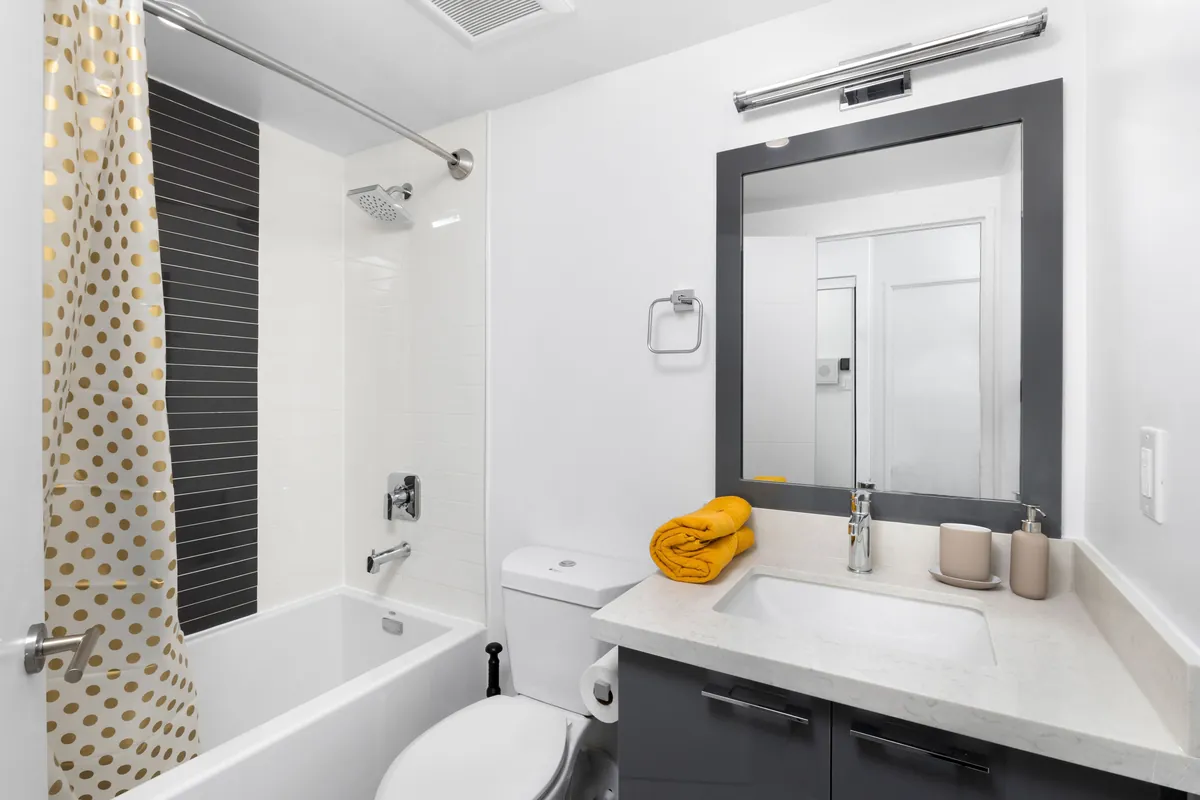Shared bathroom with a tub and large mirror