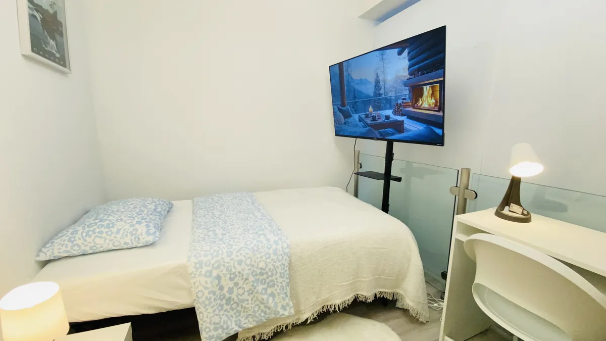 Flex bedroom with a wall-mounted television and a study desk